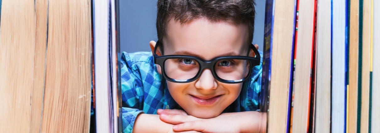 Happy pupil in glasses against books