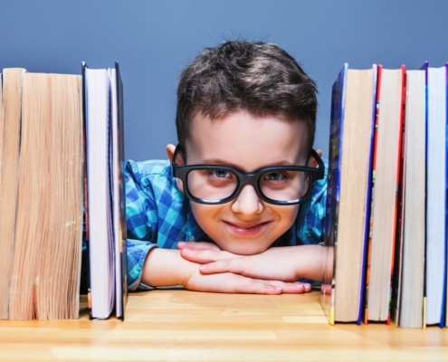 Happy pupil in glasses against books