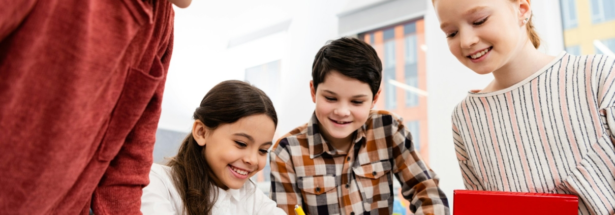 Smiling pupils with notebook and books discussing in classroom