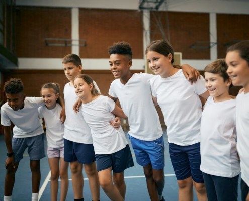 Multi-ethnic group of happy school children having PE class at at school gym.